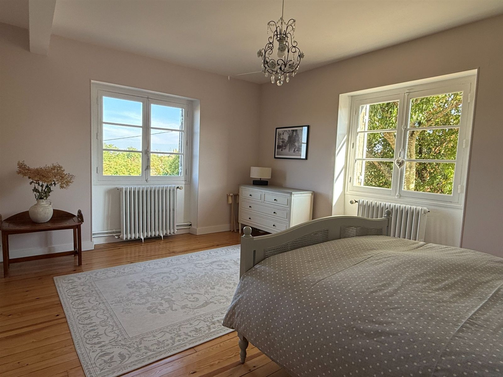 Pink bedroom with two tall windows and a garden view