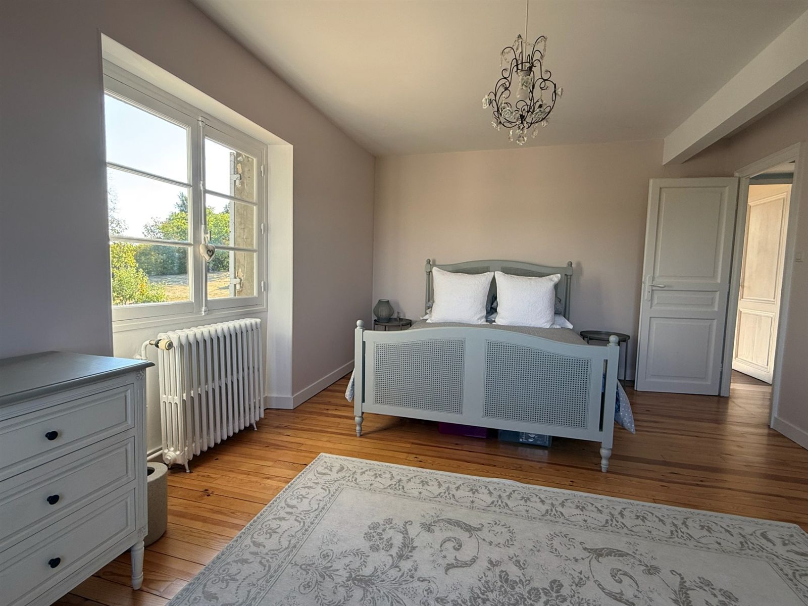 Pink bedroom with timber floor and garden-facing windows