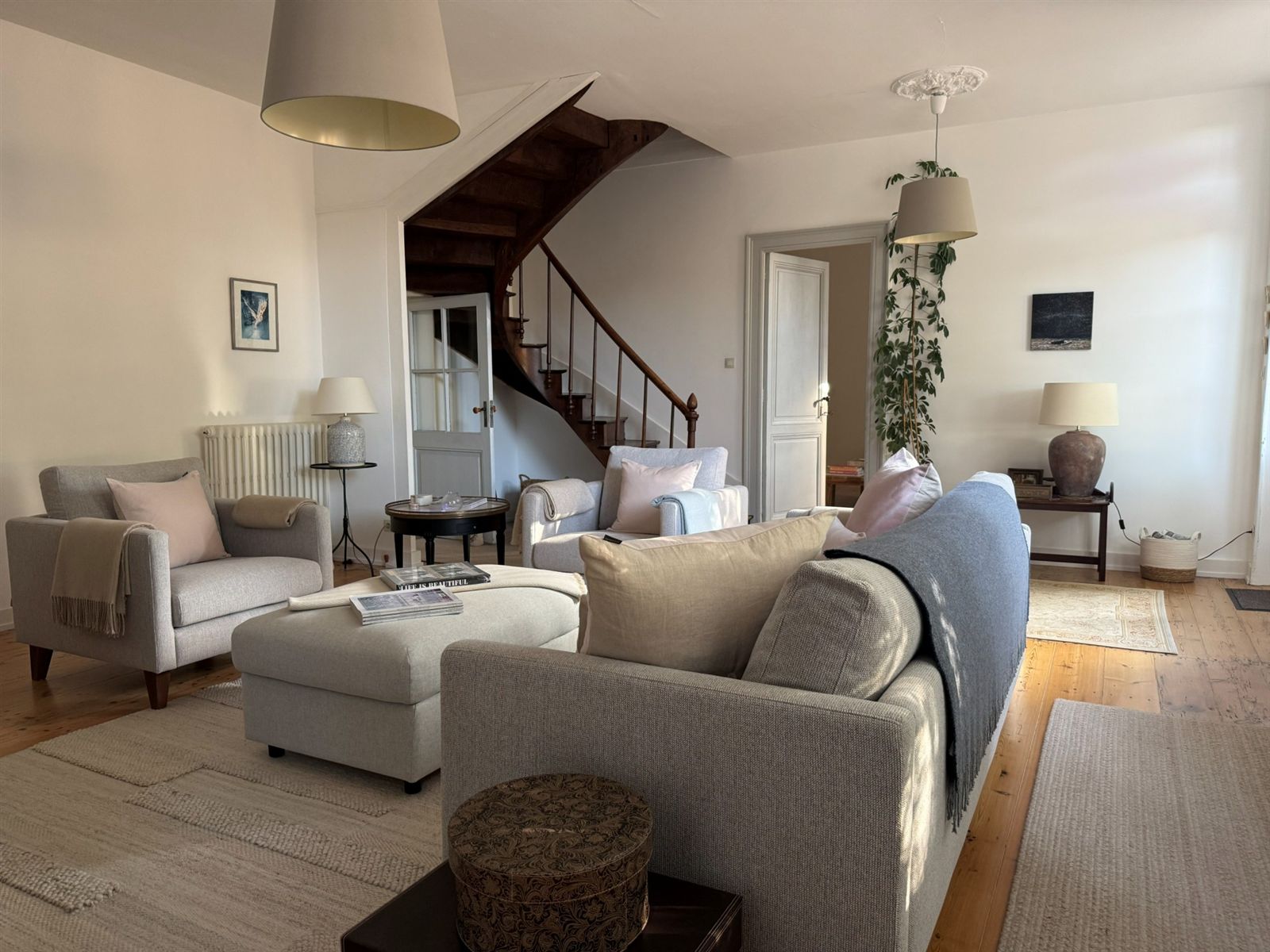 Calm entrance lounge with pale sofas and timber staircase