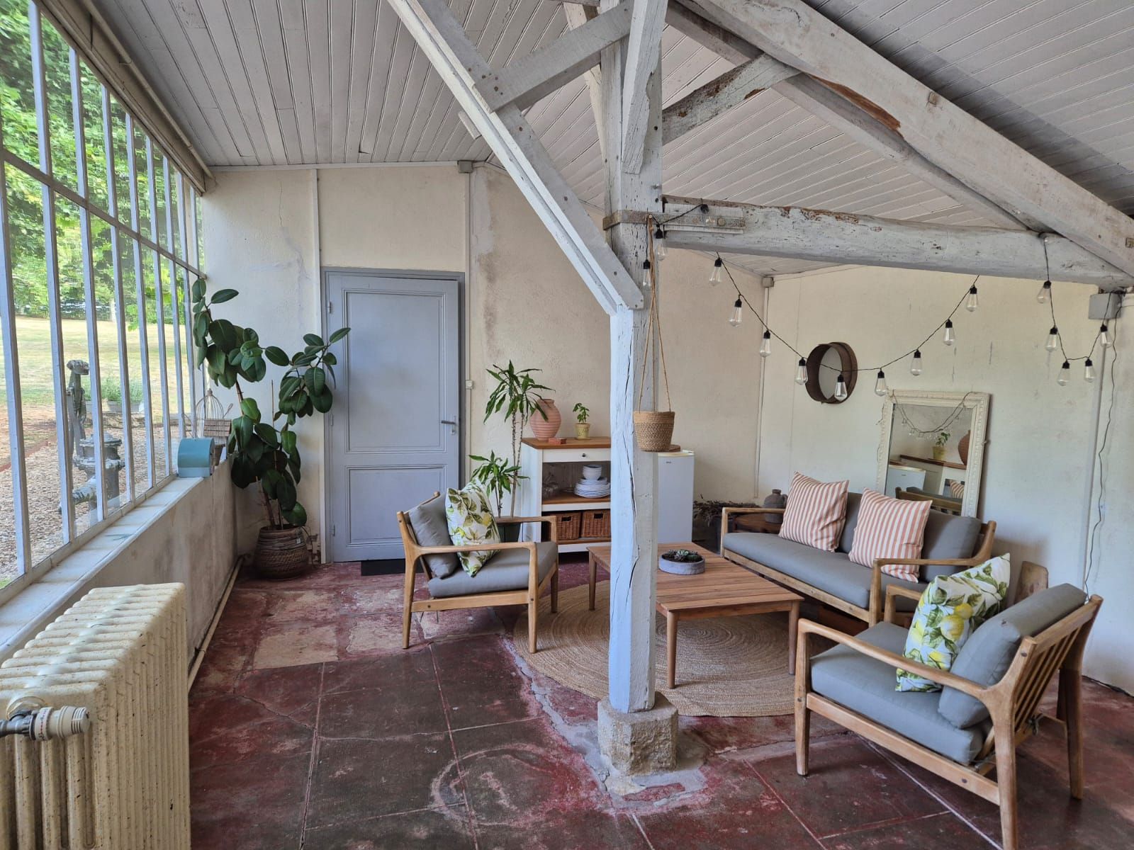 Seating area inside the Verrière with tall garden glazing and exposed roof beams